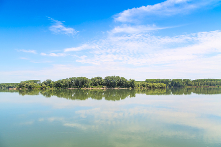 Reflection of trees, clouds and blue sky in the lake waterの写真素材