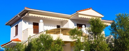 Summer vacation banner background with olive trees and white house with red roof in Greece islandの写真素材
