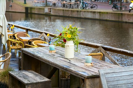 Cafe wooden table with flowers in vase and canal view in Hollandの写真素材