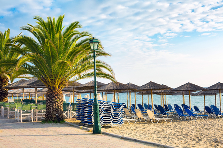 beach with umbrellas, blue sea, palm tree at travel vacation summer backgroundの写真素材