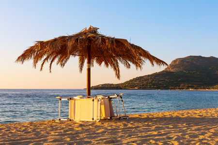 Sunset photo of chair and umbrella on the beach in Greeceの写真素材