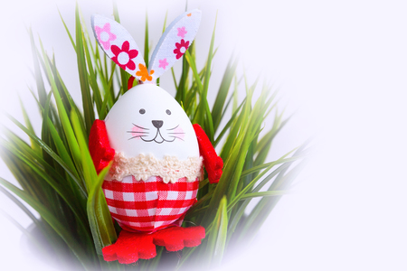 Funny Easter egg bunny rabbit decorations in green grass postcard holiday backgroundの写真素材
