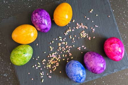 Holiday background with colorful Easter eggs on the black slate