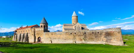 Panoramic banner view of Alaverdi orthodox monastery in Kakhetia region in Georgia and snow peaks of Caucasus mountainsの写真素材
