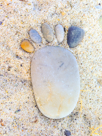 footprint made up of stones on sandy backgroundの写真素材