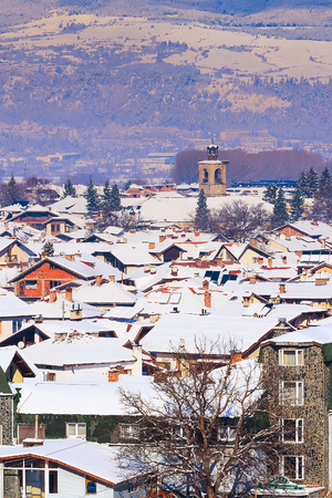 Houses with snow roofs and church tower panorama of bulgarian ski resort Bansko, Bulgariaのeditorial素材