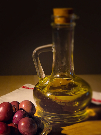 Still life with jar with olive oil and kalamata olives over black background.の写真素材