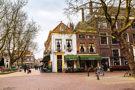 Delft, Netherlands - April 8, 2016: Street view with traditional dutch houses, bicycles, people in downtown of popular Holland destinationのeditorial素材