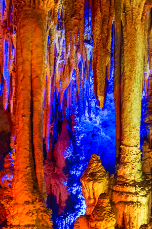 cave yellow and blue illuminated flowstones, stalactites and stalagmitesの写真素材