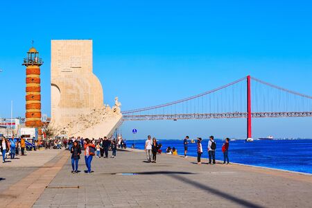 Lisbon, Portugal - March 27, 2018: People near River Tagus, Ponte de 25th Abril bridge and Monument...