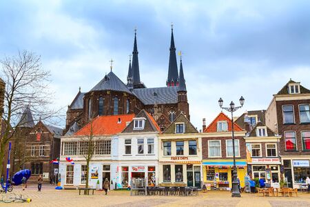 Delft, Netherlands - April 8, 2016: Colorful street view with traditional dutch houses, cathedral, bicycles, people in downtown of popular Holland destinationのeditorial素材