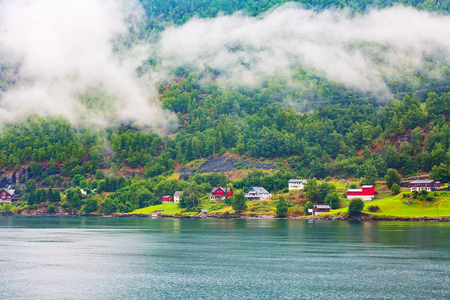 Norwegian fjord village in clouds and Sognefjord landscape near Flam, Norway. Tourism vacation and travel backgroundの写真素材
