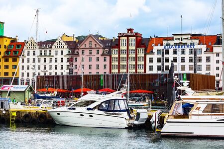 Bergen, Norway - July 30, 2018: City street view with people and colorful traditional houses, boats on water