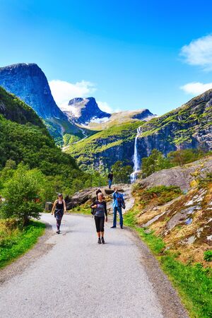 Norway, Olden - August 1, 2018: People at pathway to Briksdal or Briksdalsbreen glacier with green mountains, snow and waterfallのeditorial素材