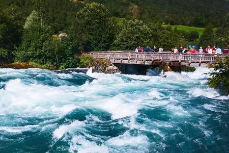 Norway, Olden - August 1, 2018: People at the bridge and turquoise water river from glacier in norwegian mountainsのeditorial素材