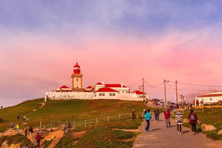 Cabo da Roca, Portugal - March 28, 2018: People near lighthouse at Atlantic Ocean, the most western point of Europe, pink sunset viewのeditorial素材