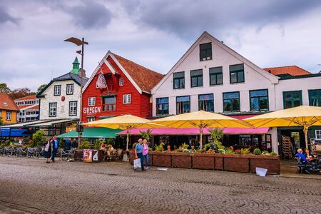 Stavanger, Norway - August 2, 2018: City street view with people, cafe, restaurants and colorful traditional wooden houses at promenade near harbourのeditorial素材