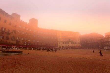 Siena, Italy - October 25, 2018: Panorama of Campo Square or Piazza del Campo with cafe, restaurants and people in Tuscany town at foggy morningのeditorial素材