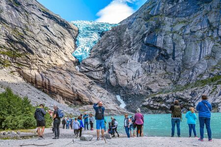 Norway, Olden - August 1, 2018: People at near lake and Briksdal or Briksdalsbreen glacier with melting blue ice, nature landmarkのeditorial素材