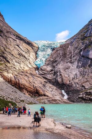 Norway, Olden - August 1, 2018: People at near lake and Briksdal or Briksdalsbreen glacier with melting blue ice, nature landmarkのeditorial素材