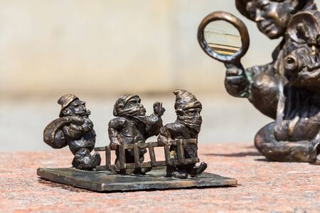 Wroclaw, Poland - June 21, 2019: Dwarf gnomes sculpture with magnifying glass in downtown of famous polish cityのeditorial素材