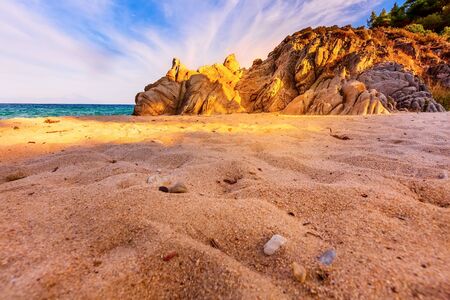 Fava sandy beach, Vourvourou, Chalkidiki or Halkidiki, Greece summer sunset scenery with turquoise sea, forest green mountains and rocksの写真素材