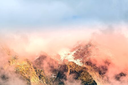Fantastic evening snow mountains landscape background. Colorful pink and blue clouds overcast sky....