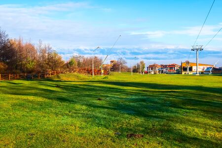 Bansko, Bulgaria - November 23, 2019: Autumn resort view with colorful trees, snow Rila mountains landscape and green grassのeditorial素材