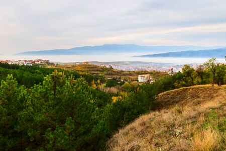 Aerial autumn morning view of Sandanski, Bulgaria with colorful forest trees and fog