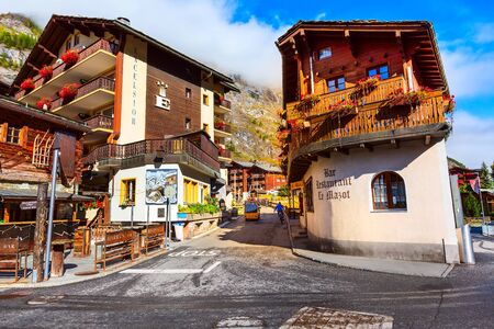 Zermatt, Switzerland - October 7, 2019: Town street view in famous swiss ski resort, colorful traditional houses, snow mountains and peopleのeditorial素材