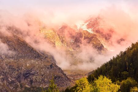 Fantastic evening snow mountains landscape background. Colorful pink and blue clouds overcast sky....