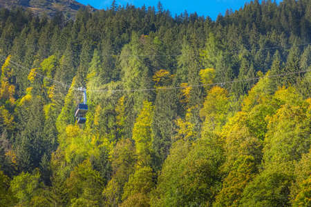 Lauterbrunnen, Switzerland - October 10, 2019: Autumn forest and blue Murrenbahn cable car in Swiss...