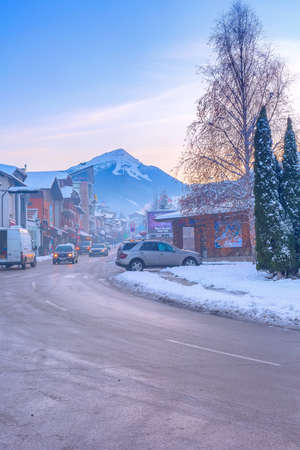 Bansko, Bulgaria - December 6, 2019: Pirin street view, traditional houses and Todorka snow mountain peak in bulgarian ski resortのeditorial素材
