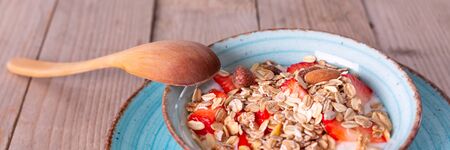 Healthy breakfast, muesli with fresh strawberry and yogurt bowl on rustic banner background