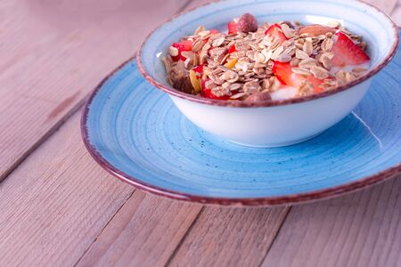 Bowl of delicious breakfast muesli with strawberry in blue ceramic bowlの写真素材