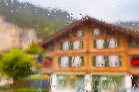 Street and house view in rainy weather through the wet window in Swiss Alpsの写真素材