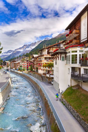 Zermatt, Switzerland - October 7, 2019: Alpine village panorama, Swiss Alps, traditional wooden houses, snow mountains and riverのeditorial素材