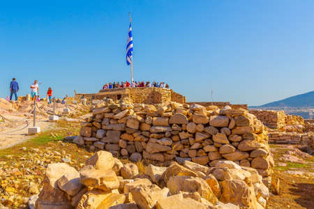 Athens, Greece - October 14, 2016: Tourists near old temple ruins and greek flag in Acropolisのeditorial素材