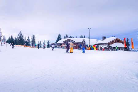 Saalbach, Austria - March 2, 2020: Skiers and snowboardes on the ski slope, wooden restaurant behindのeditorial素材