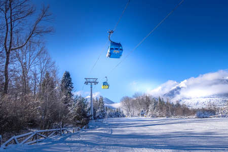 Bansko, Bulgaria - January 22, 2018: Bulgarian ski resort panorama with gondola ski lift cabin, slope and snow mountainsのeditorial素材
