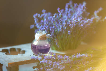 Herbal oil and lavender flowers on wooden background