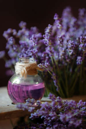 Herbal oil and lavender flowers still-life on wooden background