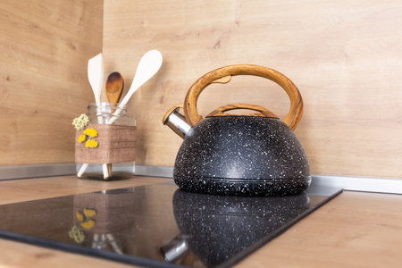 vintage granite kettle on stove top and set of kitchen spatulas in glass jar