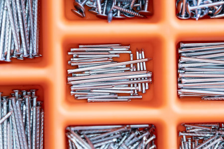 Collection of nails, screws, plastic and bolts in plastic box on the wooden table