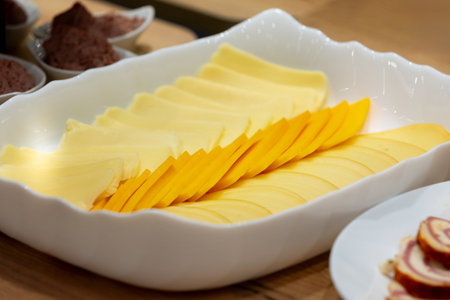 thin slices of yellow cheese on serving plate, buffet breakfast. Catering concept.の写真素材