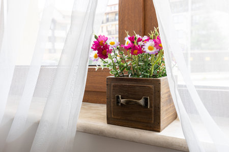 Artificial plant pink flower in flowerpot on window sill indoors, interior designの写真素材