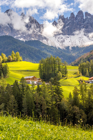 Aerial panoramic view of a village in the Dolomites, Italy, showcasing green alpine meadows and majestic mountains.の写真素材