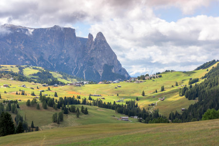 Scenic panorama of Dolomites mountain scenery with traditional wooden mountain huts at Alpe di Siusi, South Tyrol, Italyの写真素材