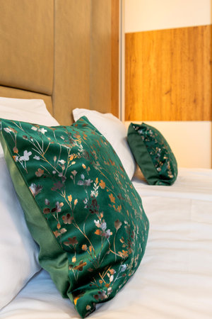 Comfortable soft white and green pillows on the bed, guest accommodation readyの写真素材