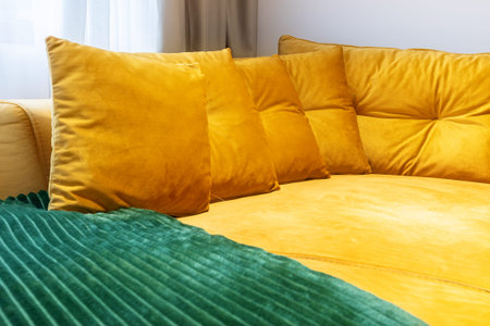 Bright yellow velvet sofa with matching pillows and green ribbed blanket in cozy home interior